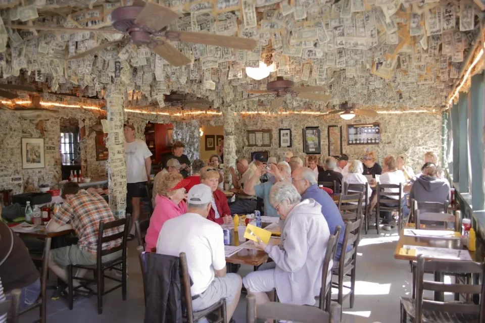 Cabbage Key Restaurant patrons enjoying a meal in the dollar bill bar at Cabbage Key. A sea of thousands of individually signed dollar bills hang from the walls and ceiling.
