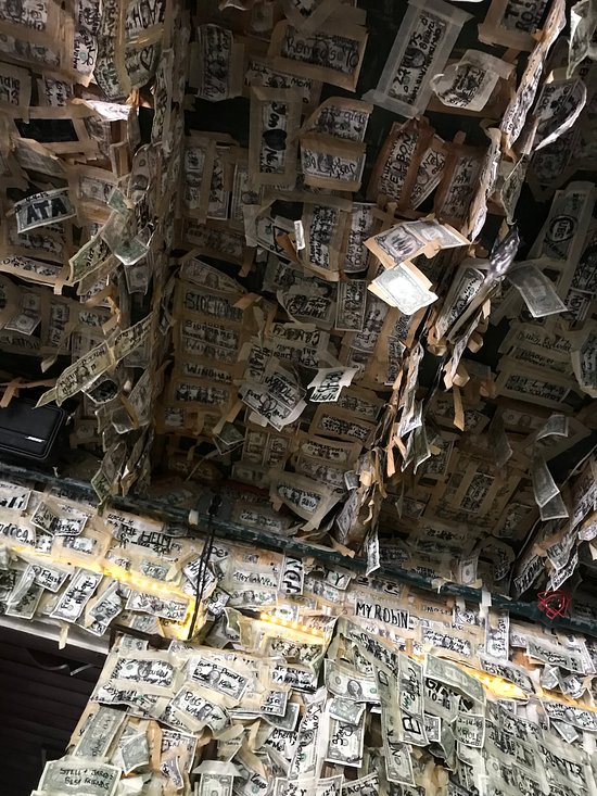 many, many dollar bills taped to ceiling and walls