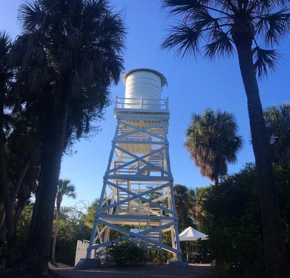 The historic wooden water tower on Cabbage Key stands tall and white against clear blue sky