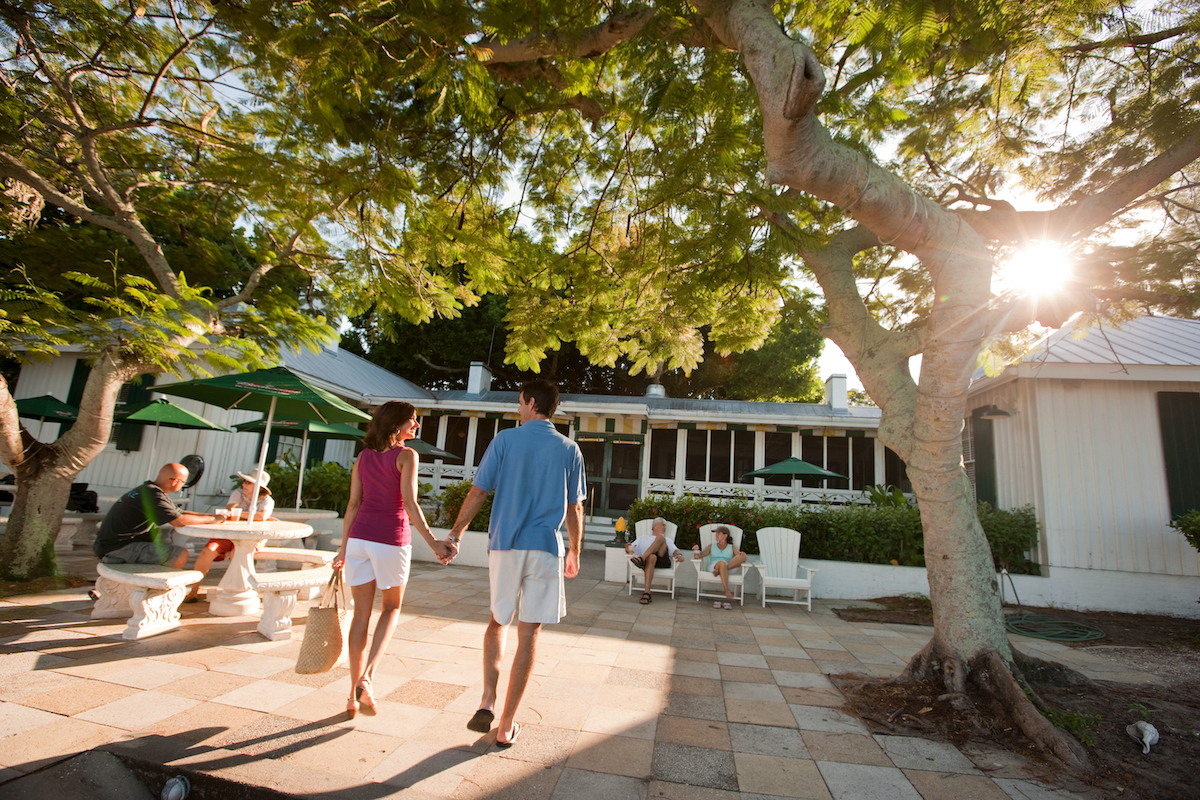 Sunlight pierces the tree canopy as a couple holds hands as they approach Cabbage Key Inn and Restaurant